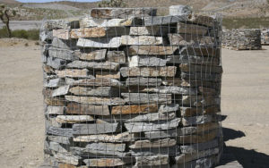 A wire cage carrying stacks of stone tiles